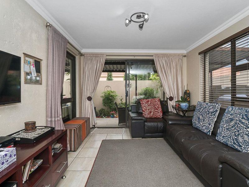 A comfortable living room featuring tiled flooring, large sliding glass doors providing access to the patio, and neutral wall finishes.