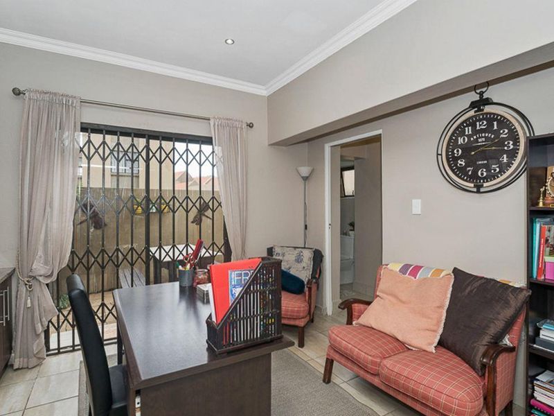 A functional living area featuring tiled flooring, built-in cabinetry, and a sliding glass door with a security gate leading to the exterior.
