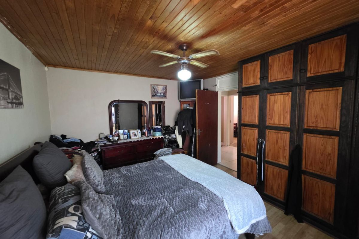 A bedroom featuring a timber-clad ceiling, ceiling fan, and extensive built-in wooden cabinetry providing ample storage space.