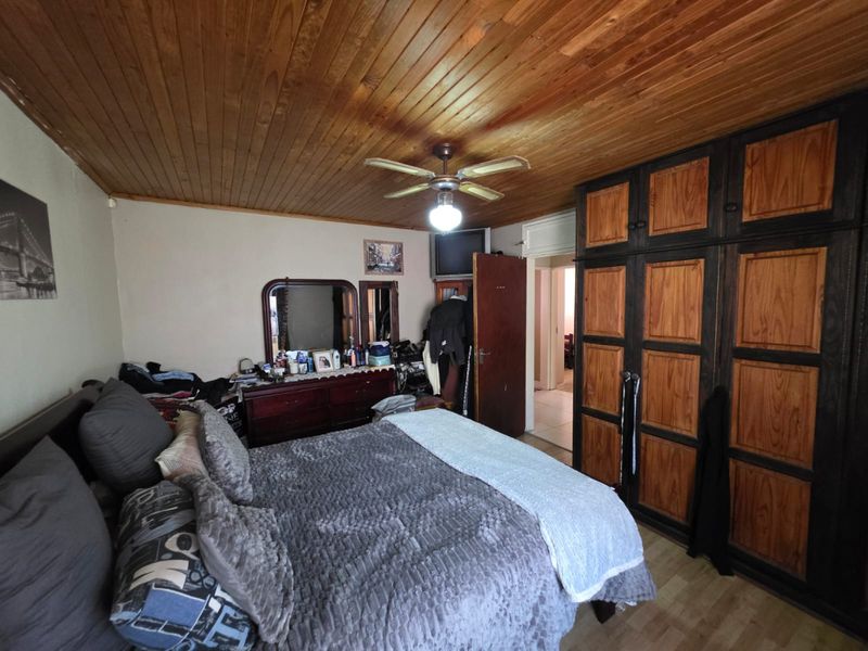 A bedroom featuring a timber-clad ceiling, ceiling fan, and extensive built-in wooden cabinetry providing ample storage space.