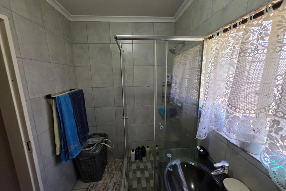 A functional bathroom featuring a glass shower enclosure, tiled walls, and a modern vanity basin with a mixer tap.