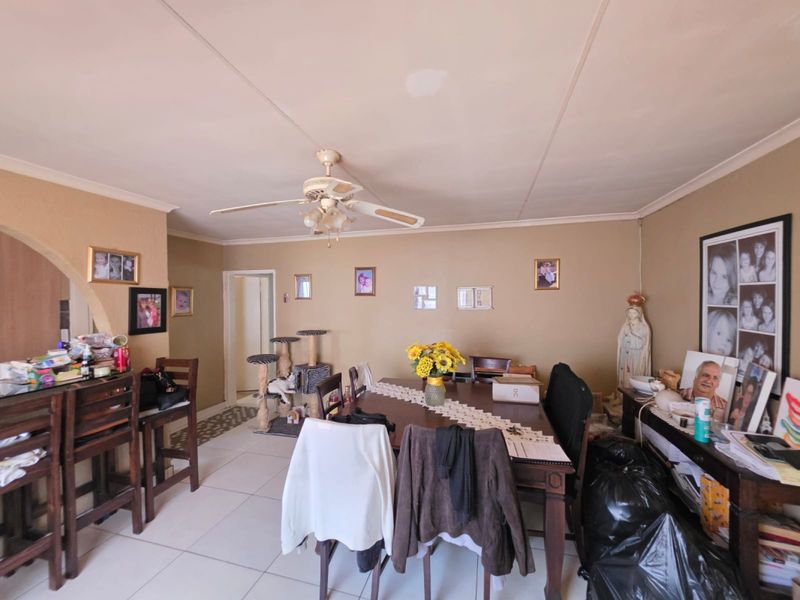 An open-plan living and dining area featuring tiled flooring, a ceiling fan, and a decorative archway leading to adjacent spaces.