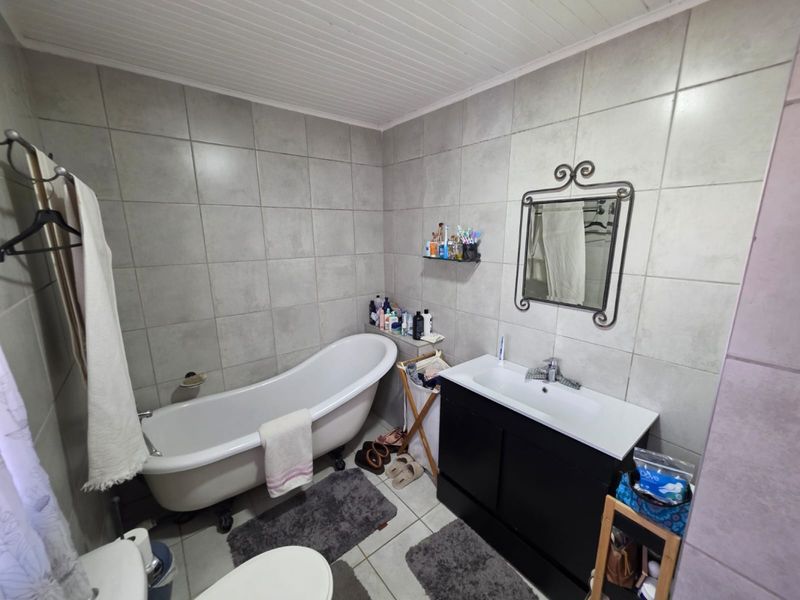 A functional bathroom featuring a freestanding bathtub, a modern vanity cabinet with a basin, and neutral wall tiling.