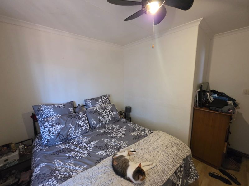 A standard bedroom featuring a ceiling fan and neutral wall finishes, providing a functional space for rest.