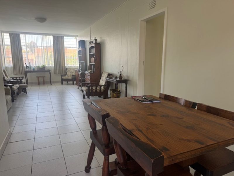 An open-plan living and dining area featuring neutral tiled flooring and large windows that provide ample natural light.