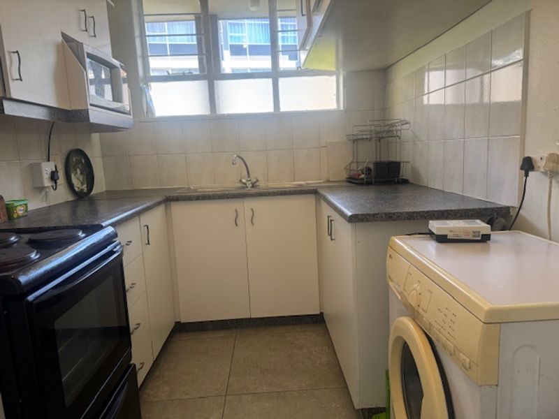 A functional kitchen featuring built-in cabinetry, laminate countertops, a tiled backsplash, and integrated appliances, offering a practical layout for daily use.