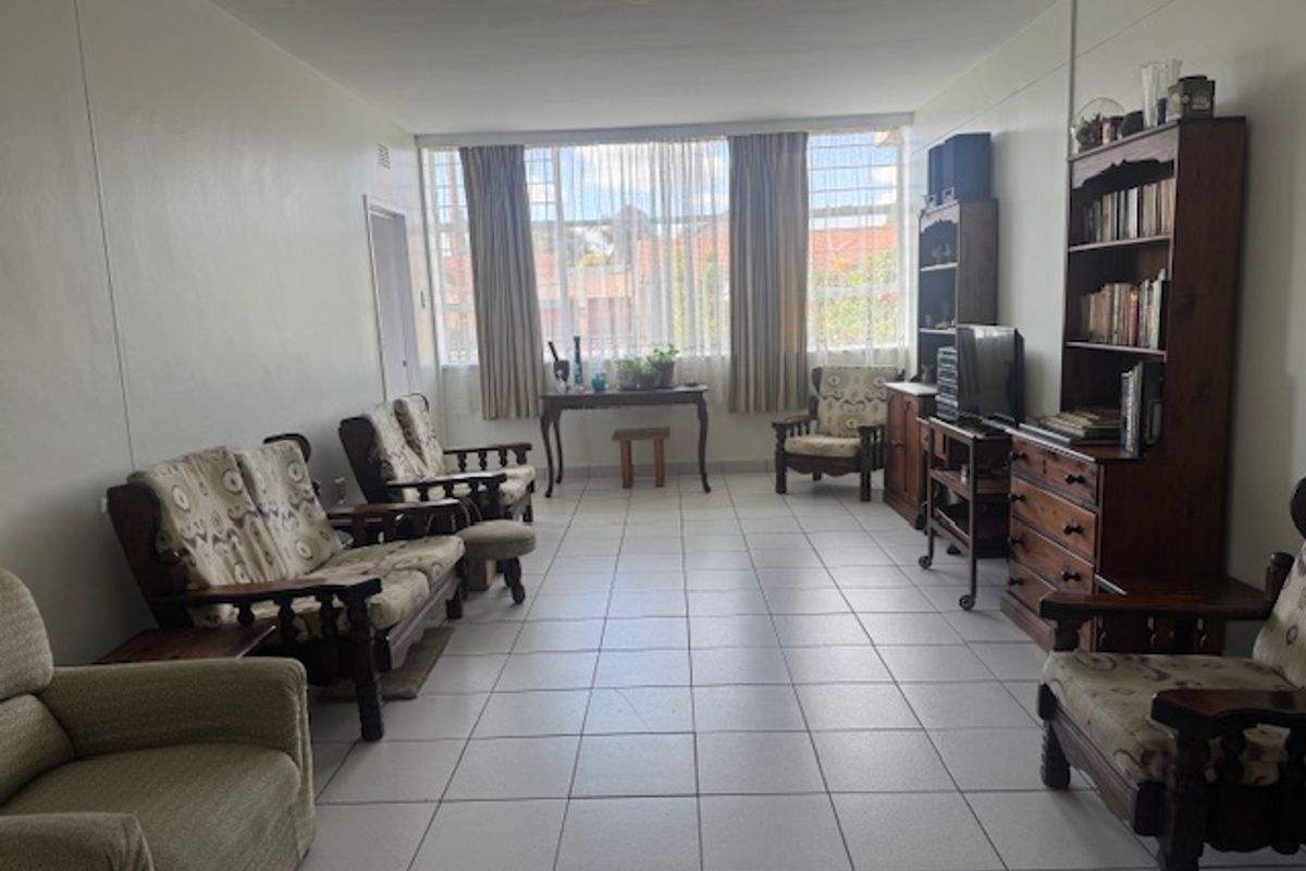 A spacious living room featuring neutral tiled flooring and a large window that allows for ample natural light.