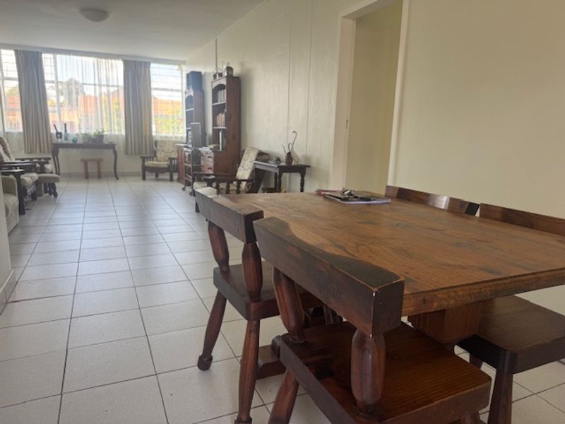 An open-plan living and dining area featuring neutral tiled flooring and large windows that provide ample natural light.