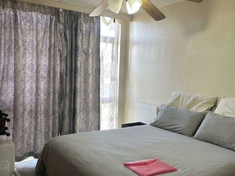 A bedroom featuring tiled flooring, a ceiling fan, and a sliding glass door providing access to the exterior.