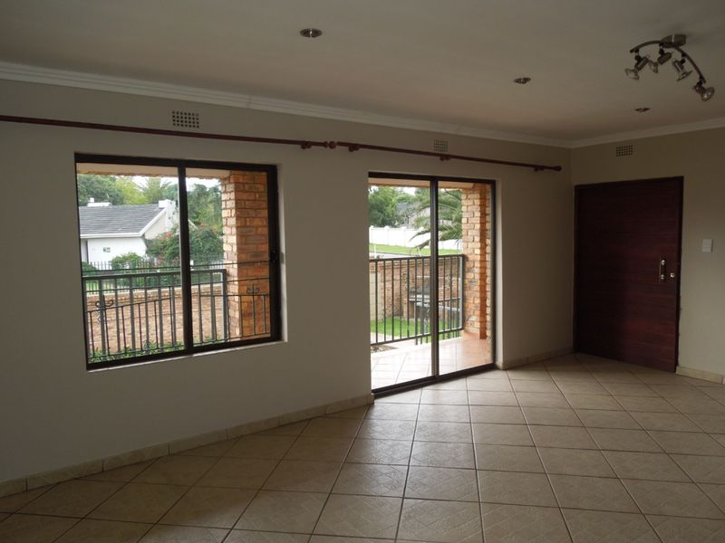 Spacious, empty living area featuring neutral tiled flooring, recessed lighting, and sliding glass doors providing access to an outdoor patio area.