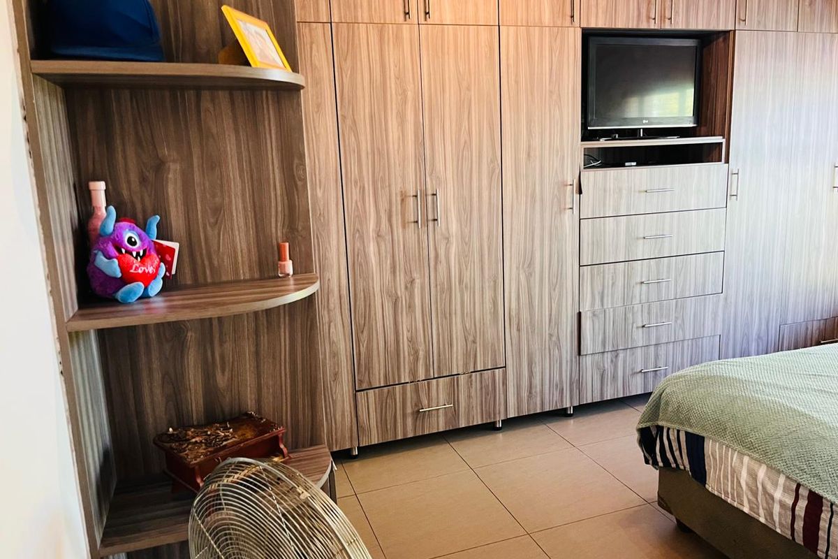 A bedroom featuring extensive built-in wooden cabinetry, including a wardrobe, integrated shelving, and a dedicated television alcove with drawers.