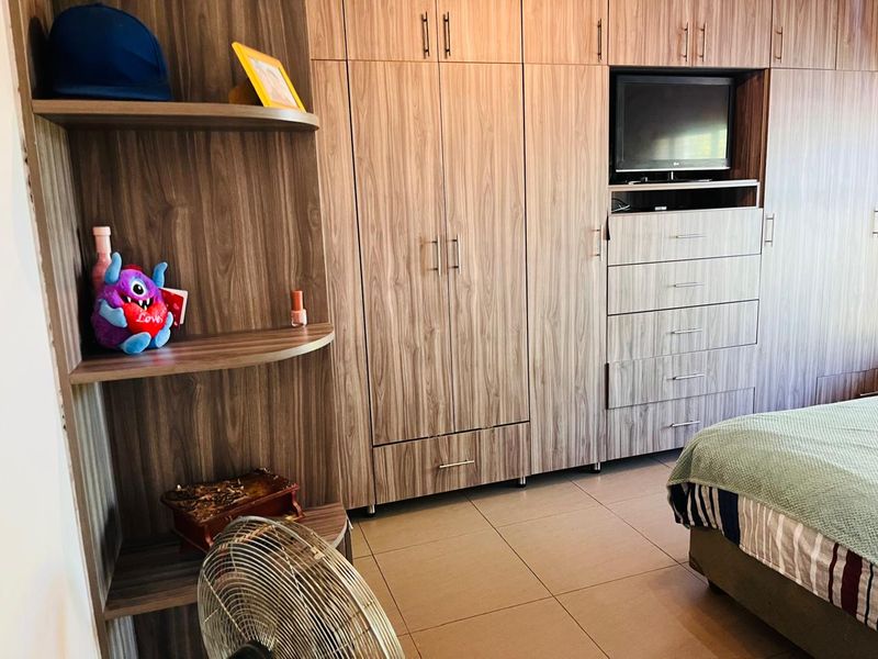 A bedroom featuring extensive built-in wooden cabinetry, including a wardrobe, integrated shelving, and a dedicated television alcove with drawers.