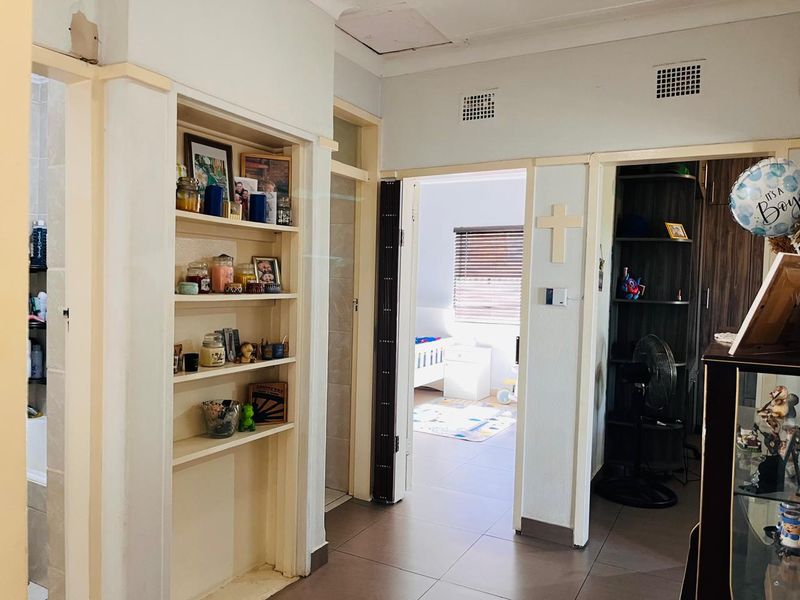 A functional hallway featuring built-in shelving, tiled flooring, and access to adjacent rooms through standard and folding doors.