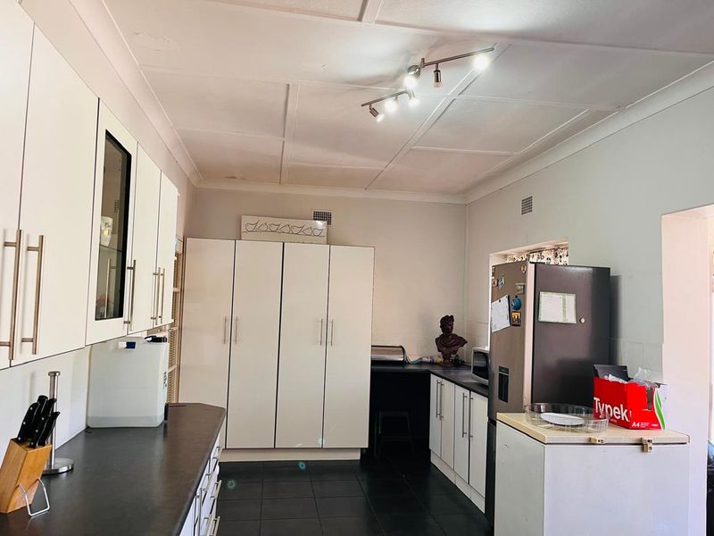 A functional kitchen featuring white built-in cabinetry, dark countertops, and tiled flooring, offering a practical layout with ample storage space.