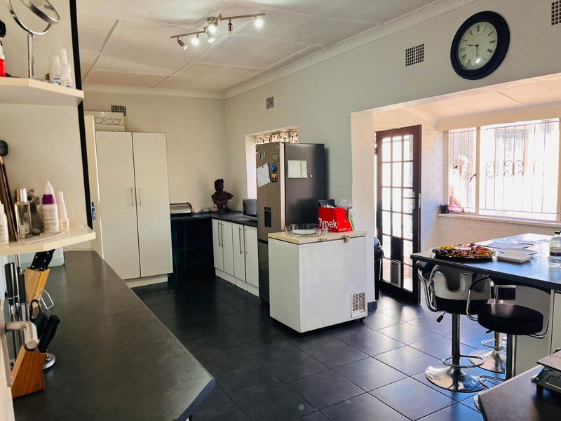 A functional kitchen featuring dark tiled flooring, built-in cabinetry, and direct access to the exterior through a glass panel door.