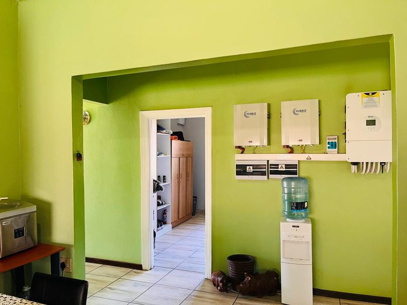 Utility area featuring a wall-mounted solar power system with dual lithium-ion batteries and an inverter, set against a bright green wall.