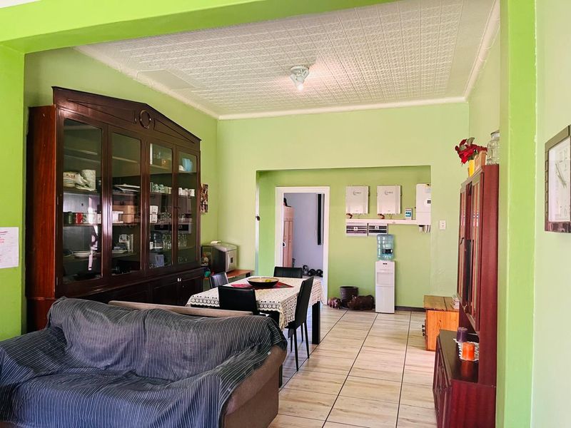 Open plan living and dining area featuring tiled flooring, textured ceiling, and wall-mounted gas water heaters.