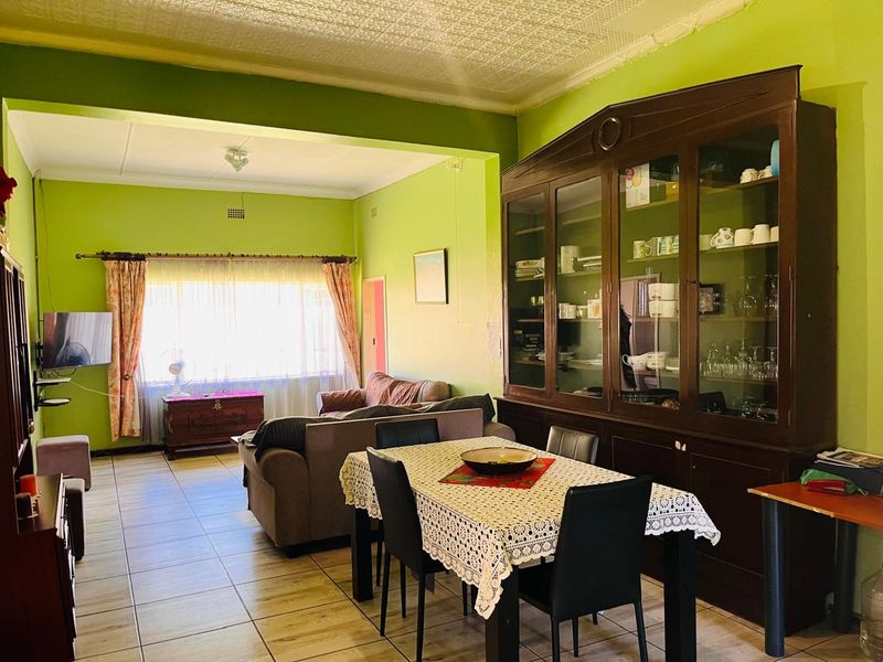 Spacious open-plan living and dining area featuring tiled flooring, a textured ceiling, and a large built-in display cabinet.