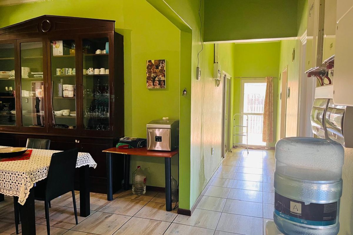A living area featuring tiled flooring and an archway leading to a hallway, with visible wall maintenance required.