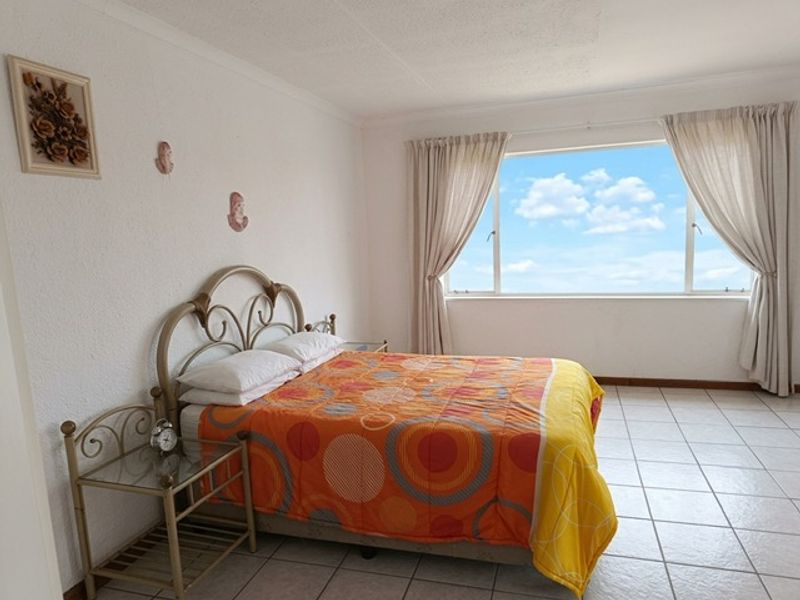 A bright bedroom featuring tiled flooring and a large window that provides ample natural light.