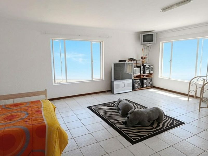 Spacious bedroom featuring large windows that provide ample natural light and tiled flooring throughout.