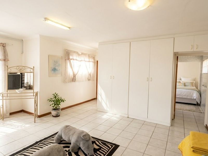 Spacious bedroom featuring built-in cupboards, tiled flooring, and direct access to an en-suite bathroom.