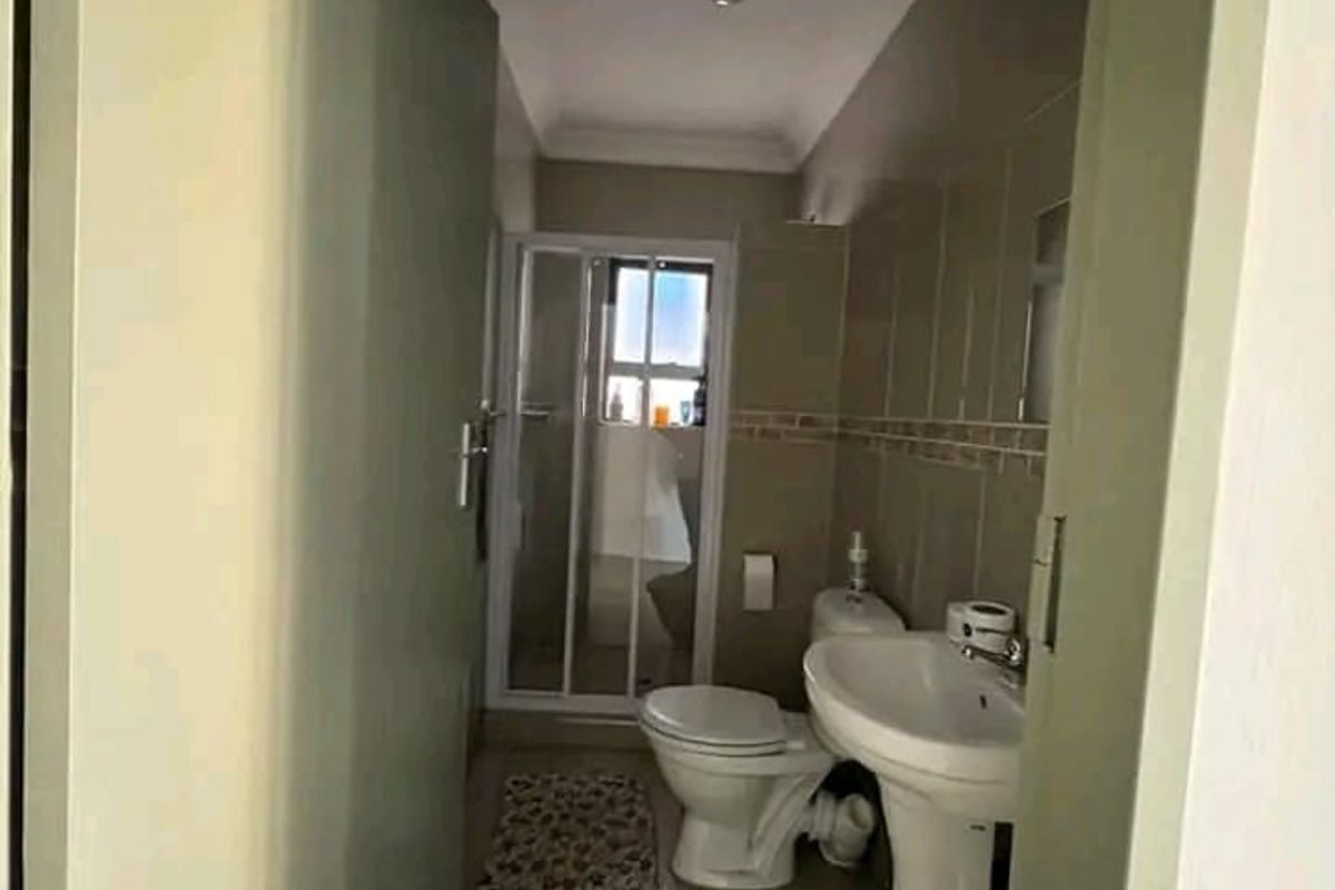 A compact bathroom featuring a pedestal sink, toilet, and a separate shower enclosure with tiled walls and flooring.