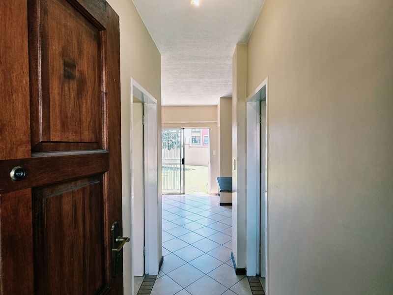 An entry hallway featuring tiled flooring and a solid wood front door, leading through to an open living area with a sliding glass door.