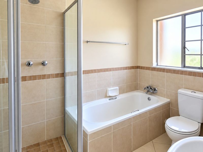 A clean, well-maintained bathroom featuring a separate shower enclosure, a built-in bathtub, and neutral tiled finishes throughout.