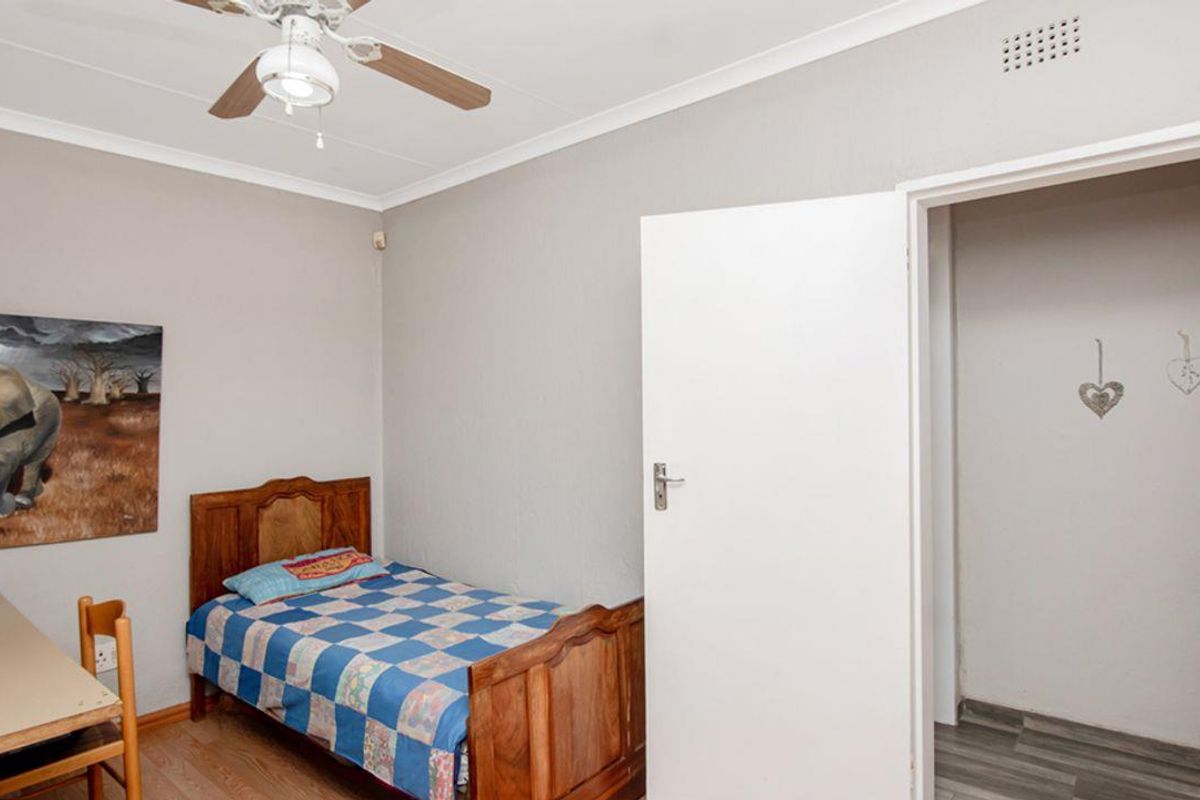 A standard bedroom featuring a ceiling fan, laminate flooring, and an adjacent walk-in closet or storage area.