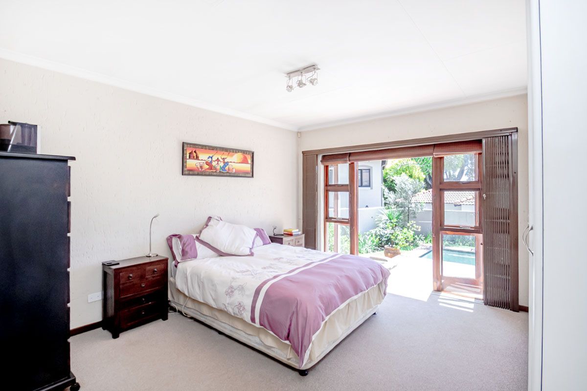 A bedroom featuring neutral walls, carpeted flooring, and sliding glass doors that provide direct access to the outdoor pool area.