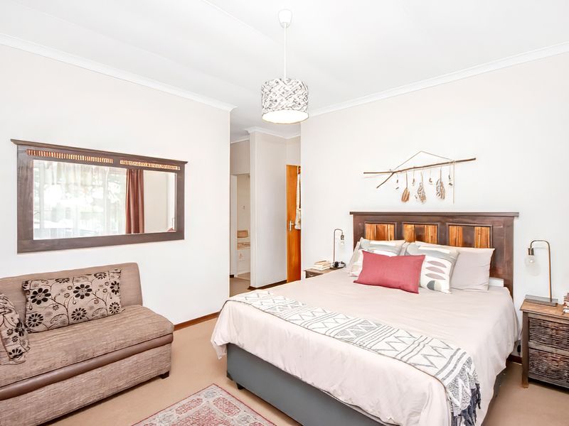 A well-lit bedroom featuring neutral walls, carpeted flooring, and a built-in doorway leading to an adjacent space.