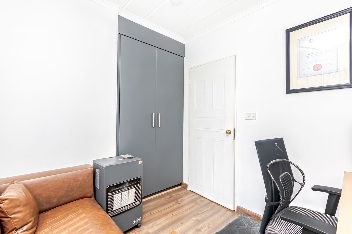 A bedroom featuring built-in grey cabinetry, wood-look flooring, and a classic panel door.