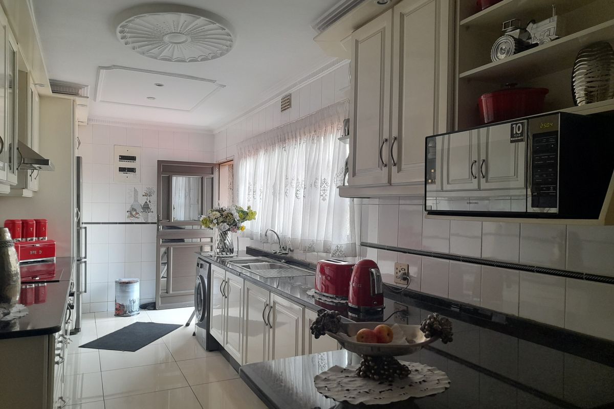 A functional kitchen featuring white cabinetry, dark granite countertops, tiled flooring, and a built-in microwave, offering a classic and practical layout.