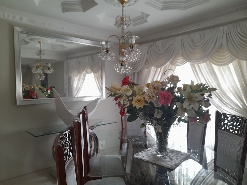 A formal dining room featuring decorative ceiling molding, a crystal chandelier, and a large wall-mounted mirror.