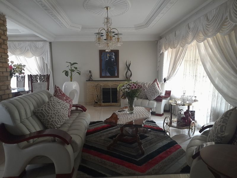 Spacious living room featuring a built-in fireplace, decorative ceiling rose, and ornate crown molding, providing a classic and formal atmosphere.