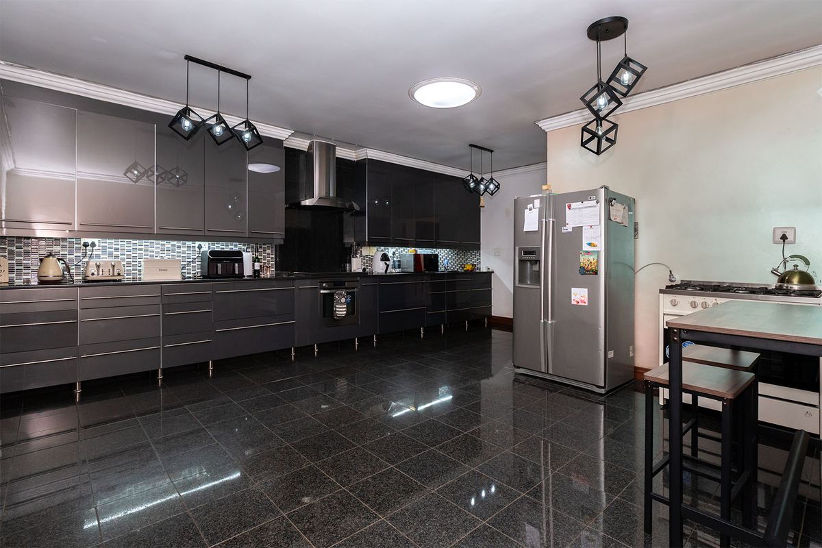 Modern kitchen featuring high-gloss grey cabinetry, granite-style tiled flooring, stainless steel extractor fan, and integrated lighting.