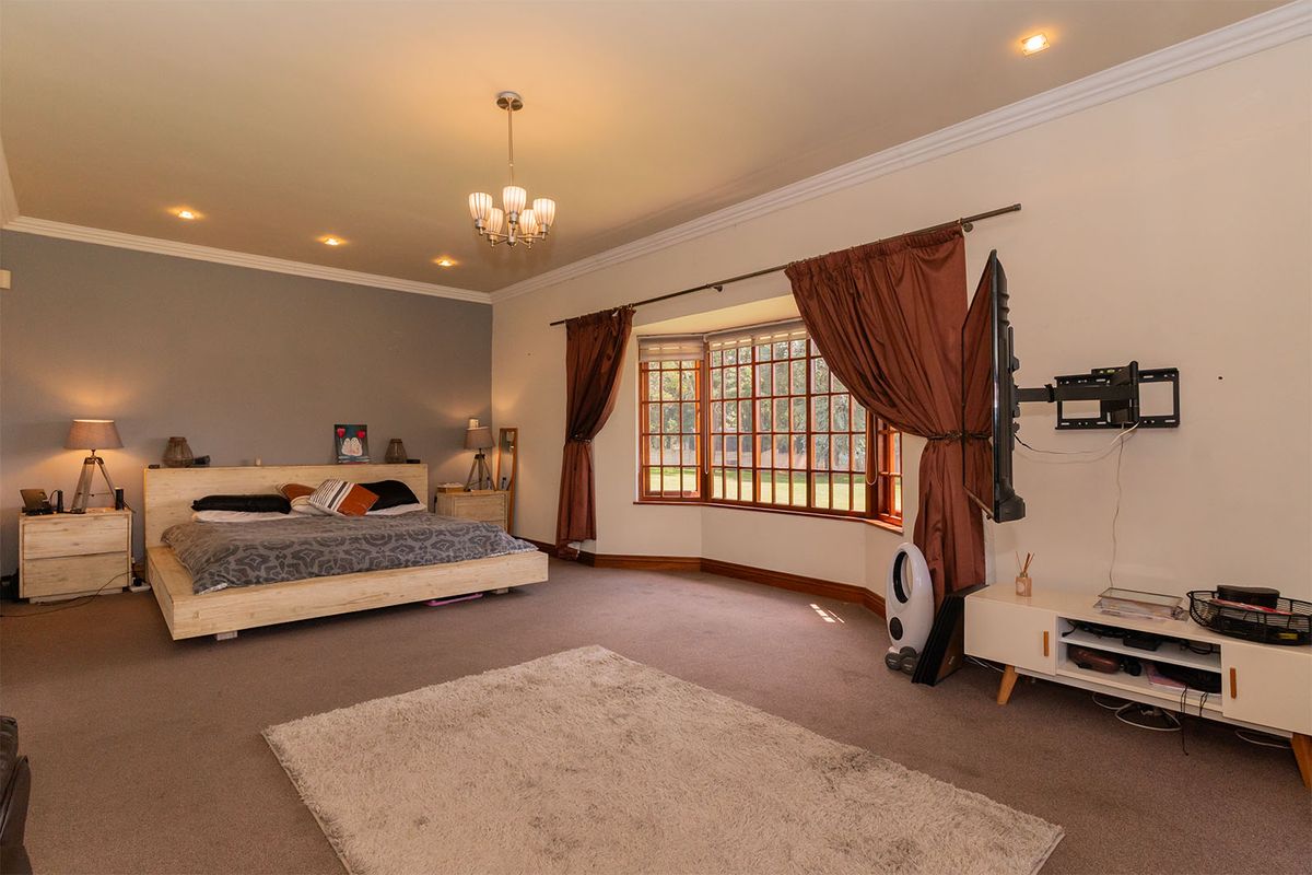 Spacious bedroom featuring a large bay window, recessed ceiling lighting, and a feature wall, offering ample natural light and a comfortable layout.