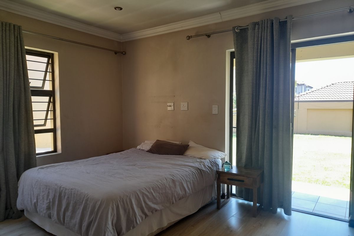 A bedroom featuring laminate flooring, crown molding, and a sliding glass door providing direct access to the rear garden.