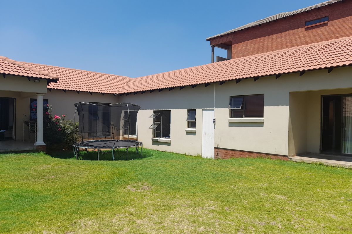 A view of the rear garden and exterior facade of the house, featuring a tiled roof, plastered walls, and access to the patio area.