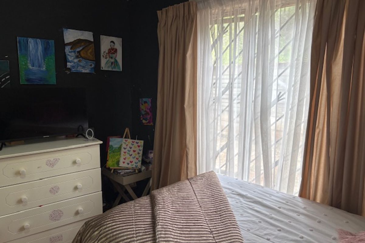 A bedroom featuring a window with installed security bars and curtain tracks, finished with dark wall paint.