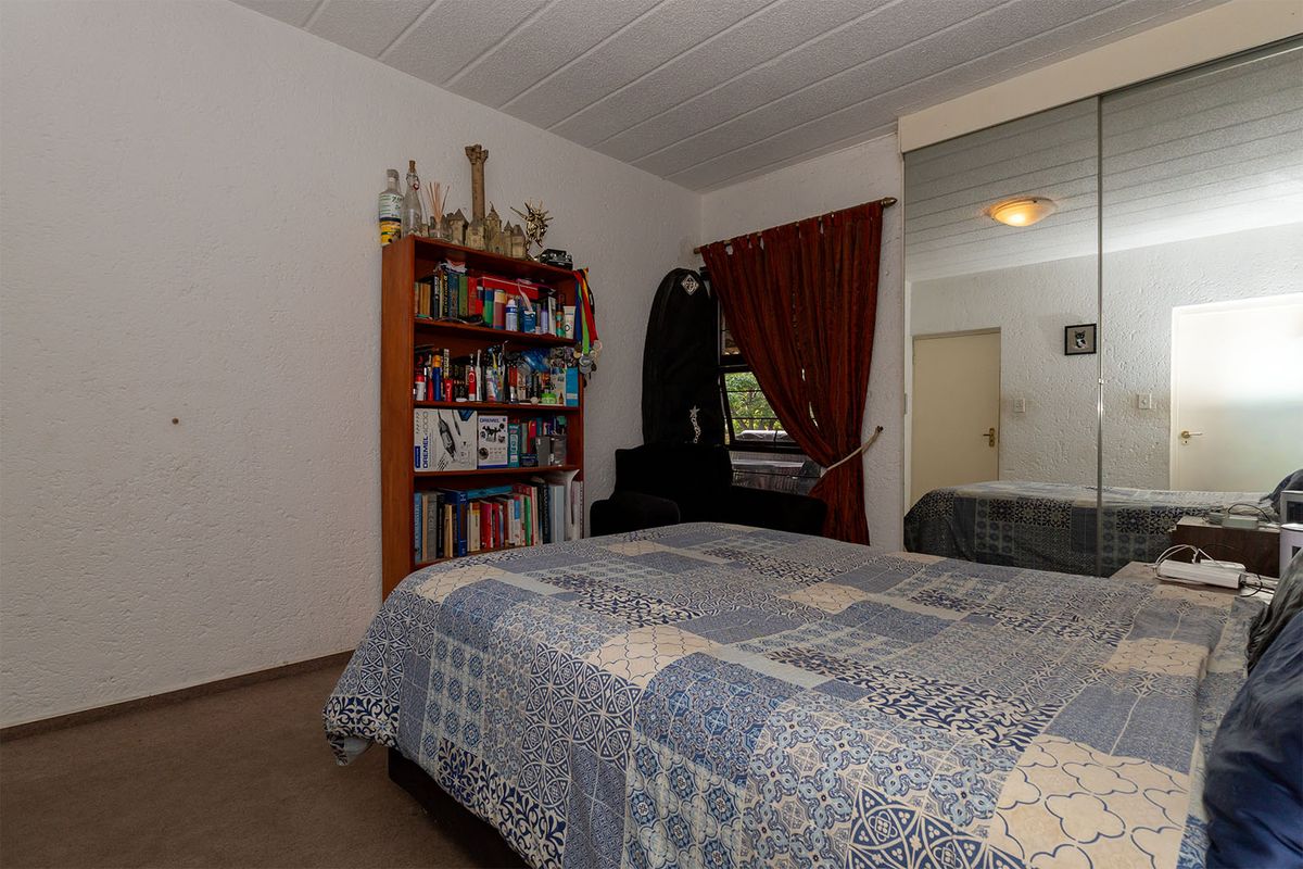 A bedroom featuring built-in mirrored sliding door cupboards and textured wall finishes.
