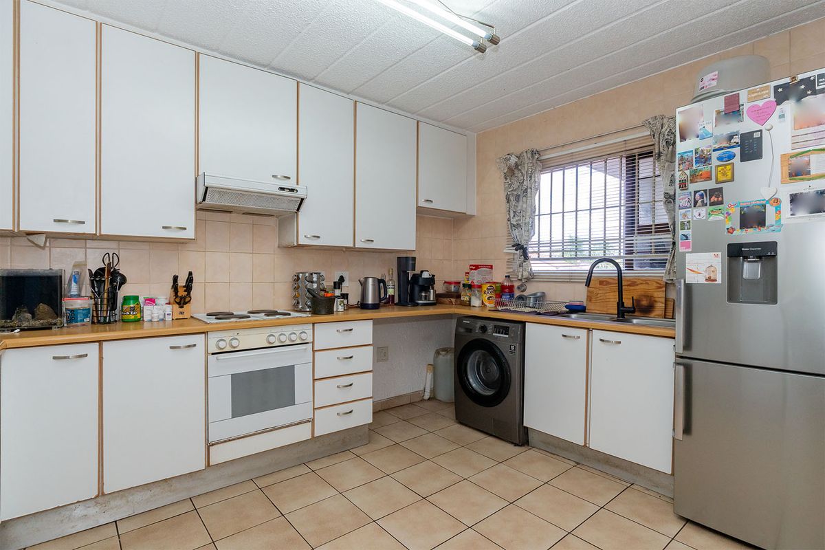 Functional kitchen featuring white cabinetry, tiled backsplash, integrated oven and hob, and space for a washing machine under the counter.