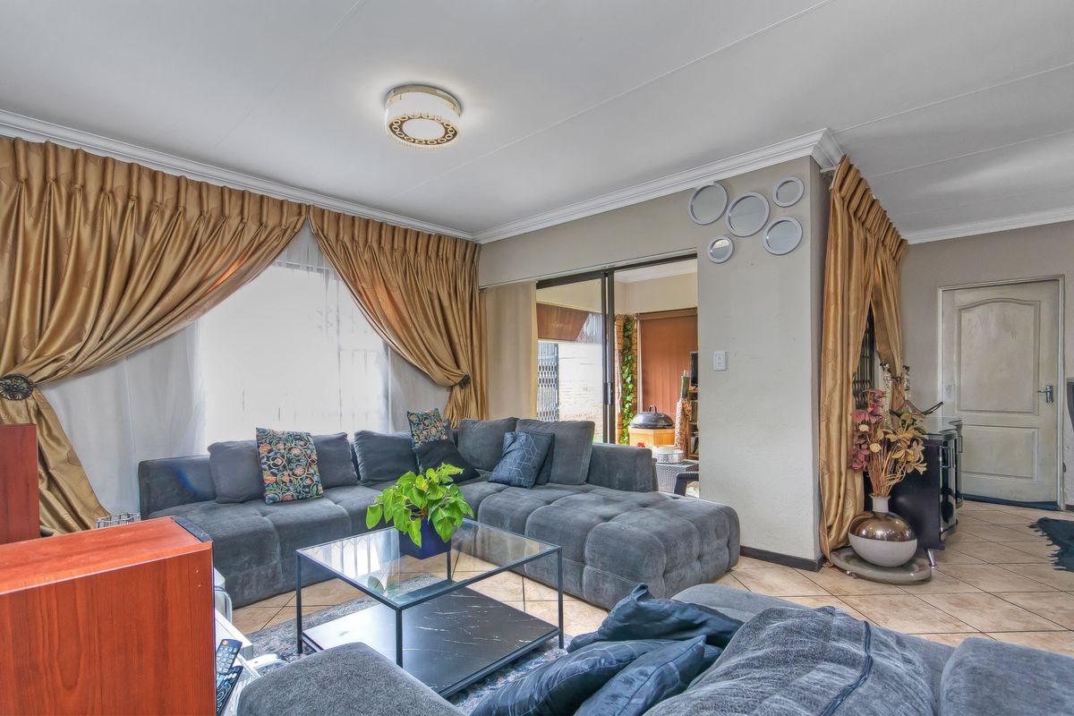 A comfortable living room featuring tiled flooring, coved ceilings, and a sliding glass door providing access to the outdoor area.