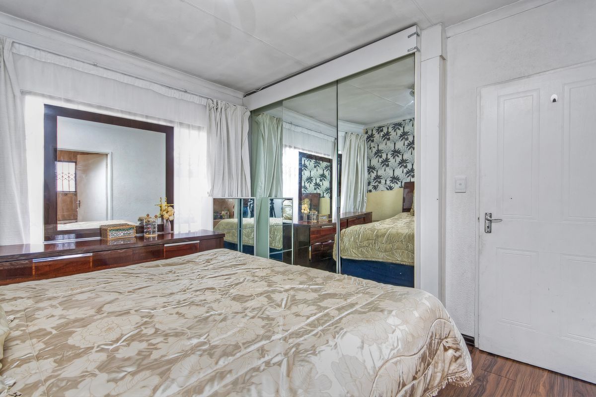 Bedroom featuring laminate flooring and a large built-in mirrored wardrobe. The room requires cosmetic attention to the ceiling finishes.
