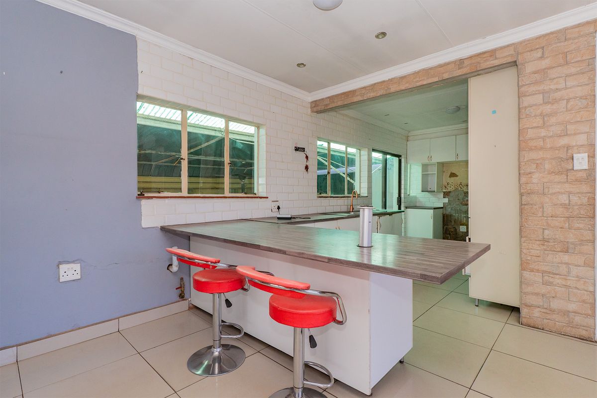 Kitchen area featuring a breakfast bar, tiled flooring, and a mix of brick and subway tile finishes, with an adjacent scullery space.