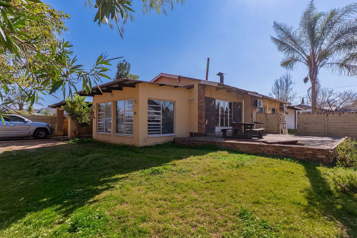 Rear view of the house featuring a brick patio, landscaped garden, and exterior wall finishes.