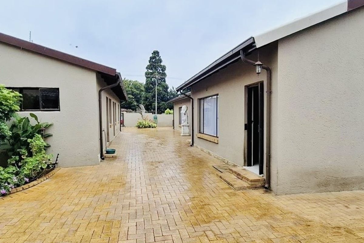 A paved courtyard area situated between two sections of the house, featuring exterior wall finishes and access points.