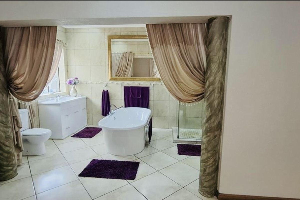 A spacious bathroom featuring a freestanding bathtub, a separate glass-enclosed shower, and a vanity unit with tiled flooring and wall finishes.