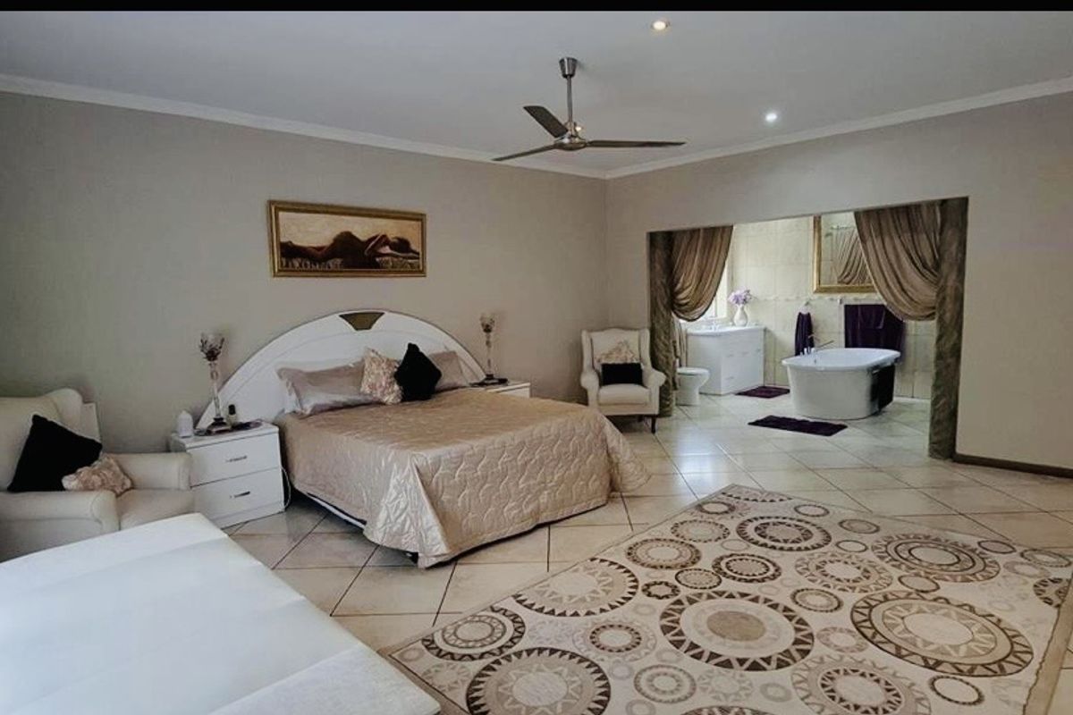 Spacious master bedroom featuring an open-plan en-suite bathroom with a freestanding bathtub and tiled flooring throughout.